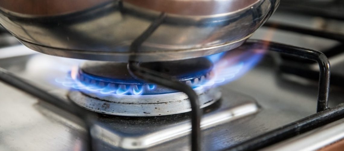 Close up of a blue gas flame, cooking a water pot in kitchen