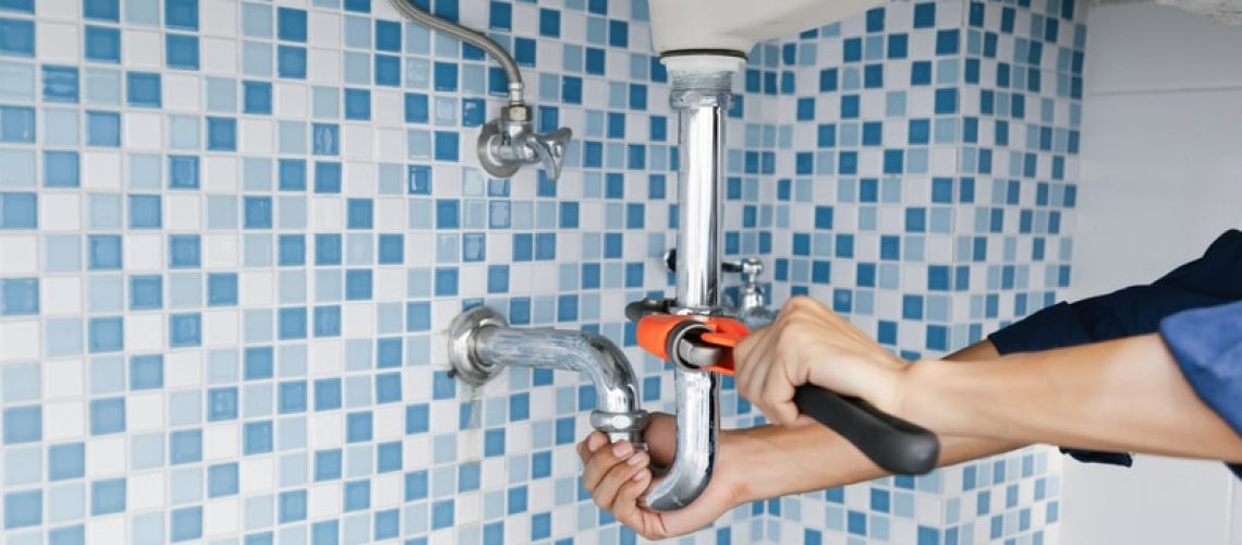 Plumber fixing sink pipe with a wrench