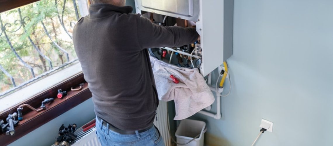 Technician Repairing Natural Gas Combi Boiler At Home